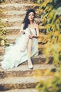 Bride in white dress sit on steps outdoor. Woman wear lace garter on leg. woman in stockings lingerie on wedding Royalty Free Stock Photo