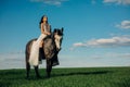 Bride in white dress sits horseback on horse on meadow