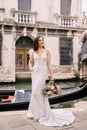 Venice wedding in Italy. A bride in a white dress, with a train, with a bouquet of white and red roses in her hands