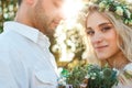 Bride in white dress and wreath and groom portrait in sunny summer day. Rustic outdoor wedding concept Royalty Free Stock Photo