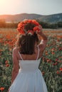 Bride in a white dress in a wreath of red poppies, warm sunset time on the background of the big red poppy field. Copy space. The Royalty Free Stock Photo
