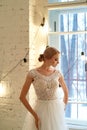 The bride in a white lace dress with embroidered bodice, indoors in loft style.High key. Royalty Free Stock Photo