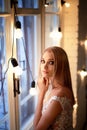 The bride in a white lace dress with embroidered bodice, indoors in loft style.Warm next to burning light bulbs. Royalty Free Stock Photo