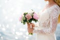 Bride in a white lace dress holds a bouquet of pink peonies in her hands Royalty Free Stock Photo