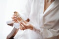 Bride in a white lace robe sitting in an armchair holds a bottle of perfume in her hands Royalty Free Stock Photo