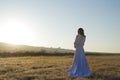 Bride in white posing in frosty field in early sunrise light Royalty Free Stock Photo