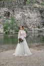 The bride in a white wedding dress on the bank of a mountain river. Royalty Free Stock Photo