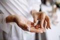 A bride in a white wedding dress and a beautiful manicure holds a gold wedding ring with a diamond with her fingers Royalty Free Stock Photo