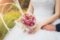 A bride in a white wedding dress is holding a bouquet in her hands. Close-up, selective focus Royalty Free Stock Photo