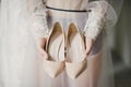 Bride in a white wedding dress holding wedding shoes in her hands Royalty Free Stock Photo