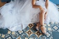 Bride in white wedding dress putting on silver shoes Royalty Free Stock Photo