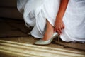 Bride in white wedding dress putting on silver shoes Royalty Free Stock Photo