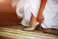 Bride in white wedding dress putting on silver shoes Royalty Free Stock Photo