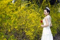 A bride with white wedding dress stand by Golden jasmine flowers Royalty Free Stock Photo
