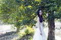 A bride with white wedding dress stand in the middle of trees Royalty Free Stock Photo
