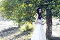 A bride with white wedding dress stand in the middle of trees Royalty Free Stock Photo