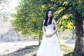 A bride with white wedding dress stand in the middle of trees Royalty Free Stock Photo