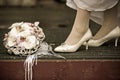 Bride in white wedding shoes stands near the wedding bouquet, vintage photo Royalty Free Stock Photo