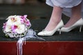 Bride in white wedding shoes stands near the wedding bouquet Royalty Free Stock Photo