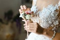 Bride woman in an elegant lace wedding dress holding a boutonniere of small white flowers. Wedding accessories Royalty Free Stock Photo