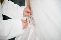 Bride& x27;s friend helps her dress in white wedding dress, zipping it up, close-up. Morning preparation of bride for Royalty Free Stock Photo