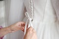 Bride& x27;s friend helps her get dressed in white wedding dress in morning, lacing it up, close-up. Morning preparation Royalty Free Stock Photo