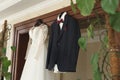 The bride& x27;s wedding dress and the groom& x27;s jacket on wooden hangers, hang on the wardrobe. Royalty Free Stock Photo