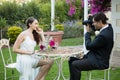 Bridegroom photographing bride while sitting at table in park