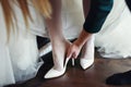 Bridemaid helps bride to put shoes on