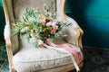 Brides wedding shoes with a bouquet with roses and other flowers on tha arm chair