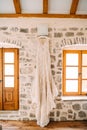 Bridesmaid dress with a skirt with flounces against the background of a stone wall and a wooden window and door, in the