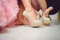 bridesmaid helping bride with golden shoes