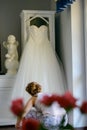 Bridesmaid helping slender bride lacing her wedding white dress, buttoning on delicate lace pattern with fluffy skirt on waist. Royalty Free Stock Photo