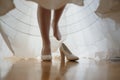 Bridesmaid helping slender bride lacing her wedding white dress, buttoning on delicate lace pattern with fluffy skirt on waist. Royalty Free Stock Photo