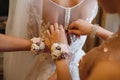 Bridesmaid helping slender bride lacing her wedding white dress, buttoning on delicate lace pattern with fluffy skirt on waist. Royalty Free Stock Photo