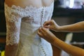 A bridesmaid helping a wedding bride to button up her dress Royalty Free Stock Photo