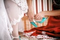 Bridesmaid helps to bride to put on wedding shoes.