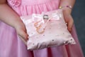 Bridesmaid holds a decorative cushion with wedding gold rings