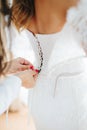 Bridesmaid laces up corset of bride`s dress, hands close-up. Wedding concept. Selective focus.