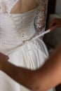 Bridesmaid makes bow-knot on the back of brides wedding dress.