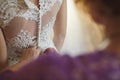 Bridesmaid makes bow-knot on the back of brides wedding dress.