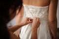 Bridesmaid making bow-knot on the back of brides wedding dress