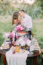 Bridesmaid is petting the face of best man at the background of the blurred table full of food located in the sunny