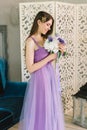 Bridesmaid in purple pink wedding dress and hair vine wreath crystal rhinestones crown tsmiles and look at bouquet of peonies duri