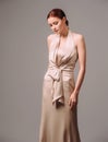 Bridesmaid`s dresses. Elegant moscato dress. Beautiful ivory silk evening gown. Studio portrait of young happy ginger woman.