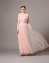 Bridesmaid`s dresses. Elegant moscato dress. Beautiful pink chiffon evening gown. Studio portrait of young happy ginger woman. Tr Royalty Free Stock Photo