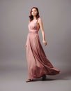 Bridesmaid's look in dust pink. Young ginger woman in summer transformer evening dress and high heel shoes