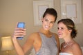 Bridesmaid taking selfie with bride in bedroom