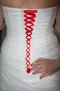 Bridesmaid tie the red laces on the back of a wedding dress closeup Royalty Free Stock Photo