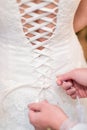 Bridesmaid tying knot on wedding dress